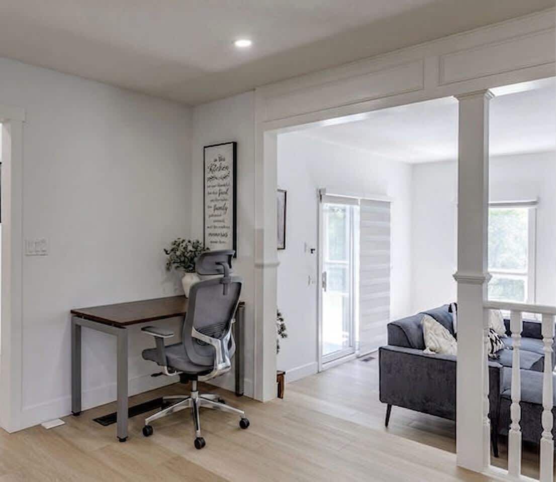 A spacious room with a desk, office chair, and a grey sofa.