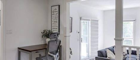 A spacious room with a desk, office chair, and a grey sofa.