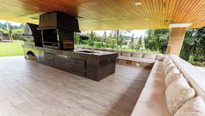 An outdoor kitchen area with a built-in grill and seating. - Mansión de lujo “La Reina” Llanogrande (Rionegro)