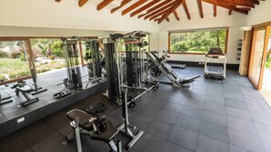 A gym with various exercise equipment, large windows, and a wooden ceiling. - Mansión de lujo “La Reina” Llanogrande (Rionegro)