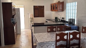 Una cocina amplia con comedor, armarios de madera y piso de baldosas.