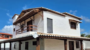 Una casa de dos pisos con un balcón, un porche cubierto y un tejado de tejas.