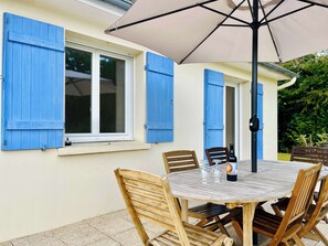 An outdoor patio with a round table, four wooden chairs, and a large umbrella. - Le Logis des Pres, Country Stay (Bricquebosq)
