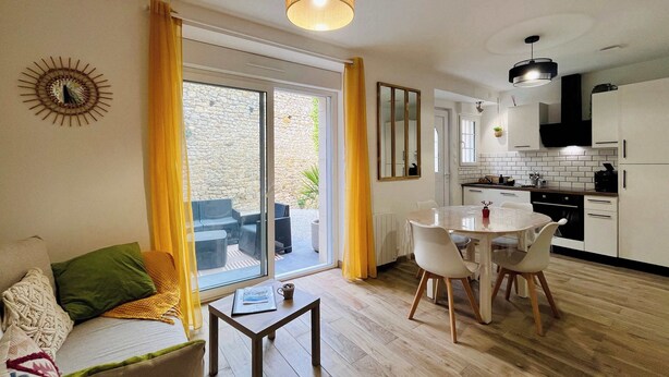 Um apartamento moderno com área de jantar, cozinha e uma grande porta de vidro deslizante para um pátio.