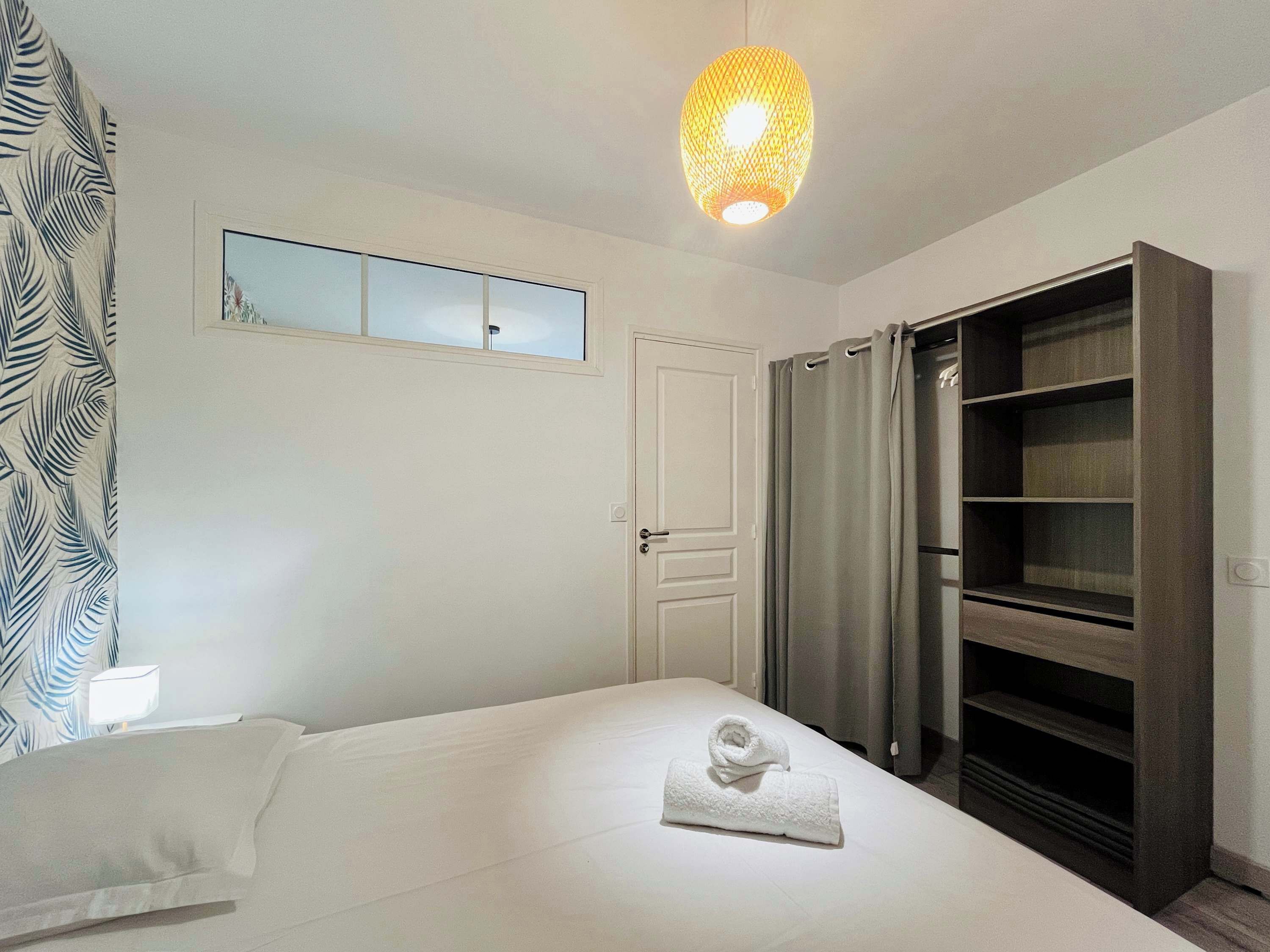 Ein Schlafzimmer mit Bett, Kleiderschrank, einer Pendelleuchte und einem Fenster mit Blick.