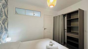Ein Schlafzimmer mit Bett, Kleiderschrank, einer Pendelleuchte und einem Fenster mit Blick.