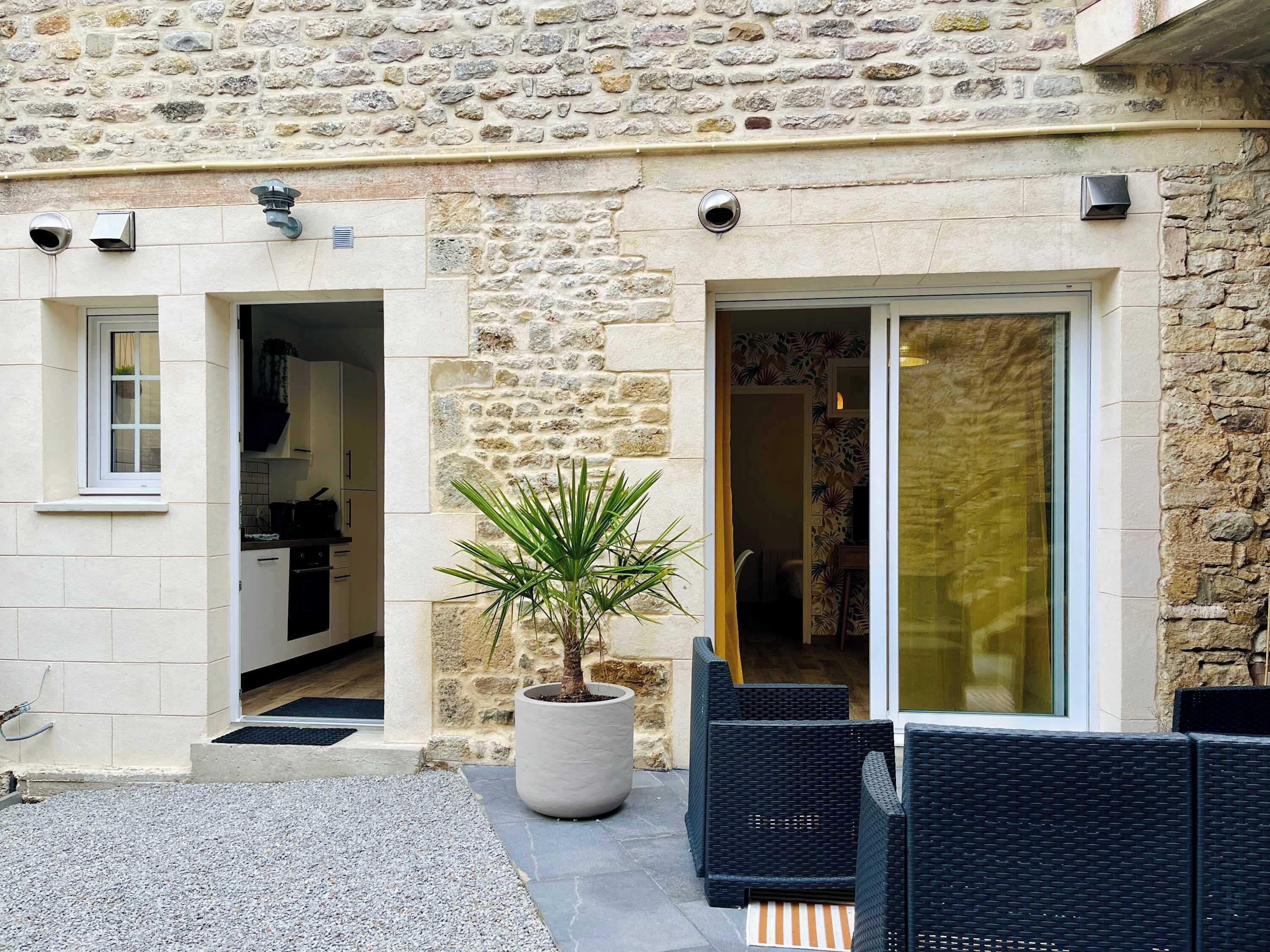 Un bâtiment en pierre doté d’une cuisine, d’une plante en pot et d’un espace extérieur aménagé pour s’asseoir.