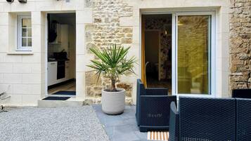 Un bâtiment en pierre doté d’une cuisine, d’une plante en pot et d’un espace extérieur aménagé pour s’asseoir.