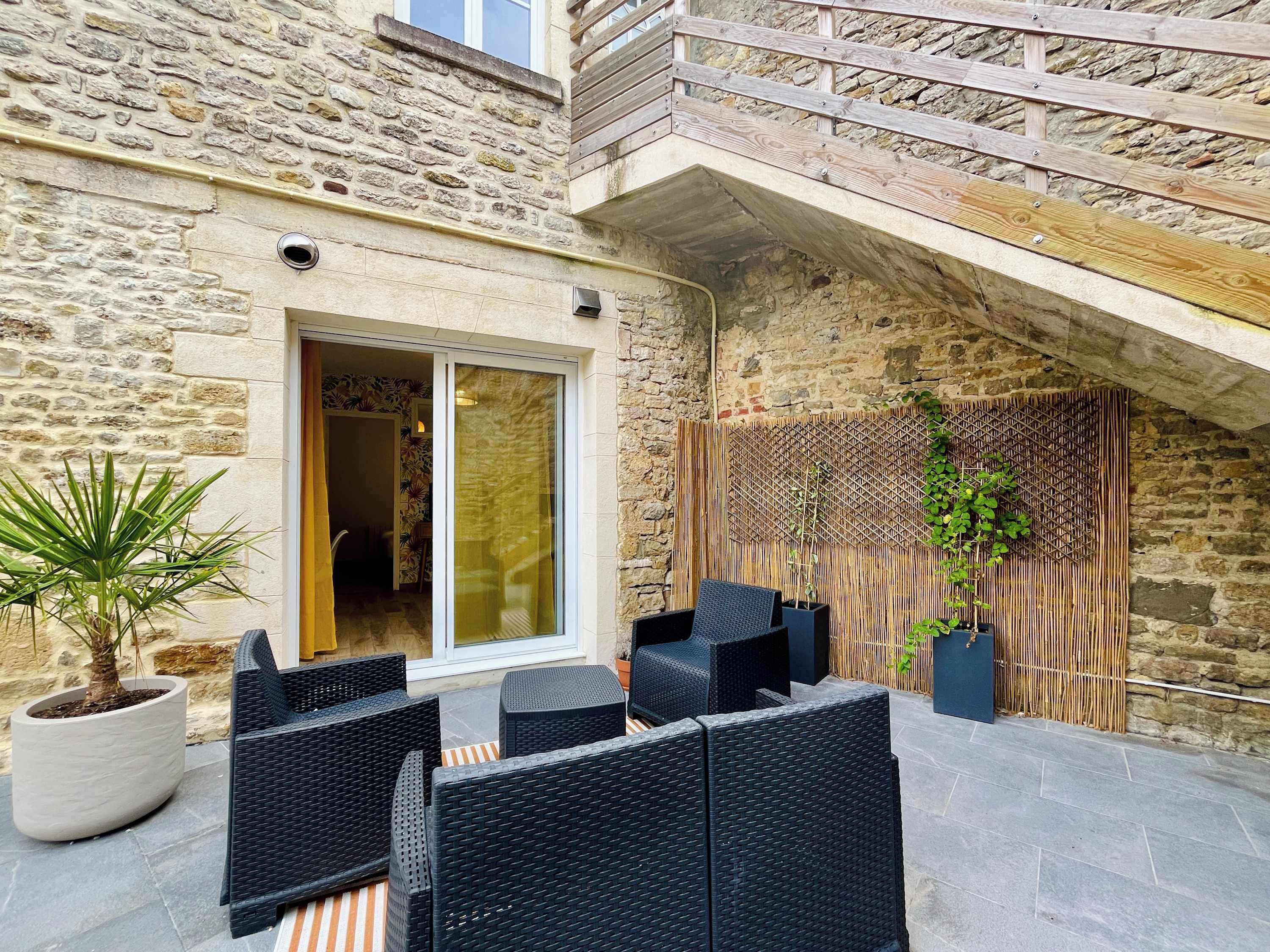 A stone building with a wooden deck, outdoor seating, and a bamboo screen.