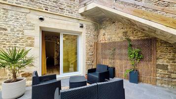 A stone building with a wooden deck, outdoor seating, and a bamboo screen.