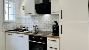 Uma cozinha moderna com armários brancos, fogão preto e cafeteira.