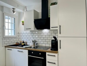 Une cuisine moderne avec des meubles blancs, une cuisinière noire et une machine à café.