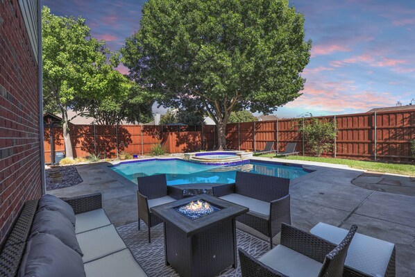 A backyard with a swimming pool, a fire pit, and outdoor furniture. - 5BR Frisco Pool• Near Universal Studios & The Star (Frisco)