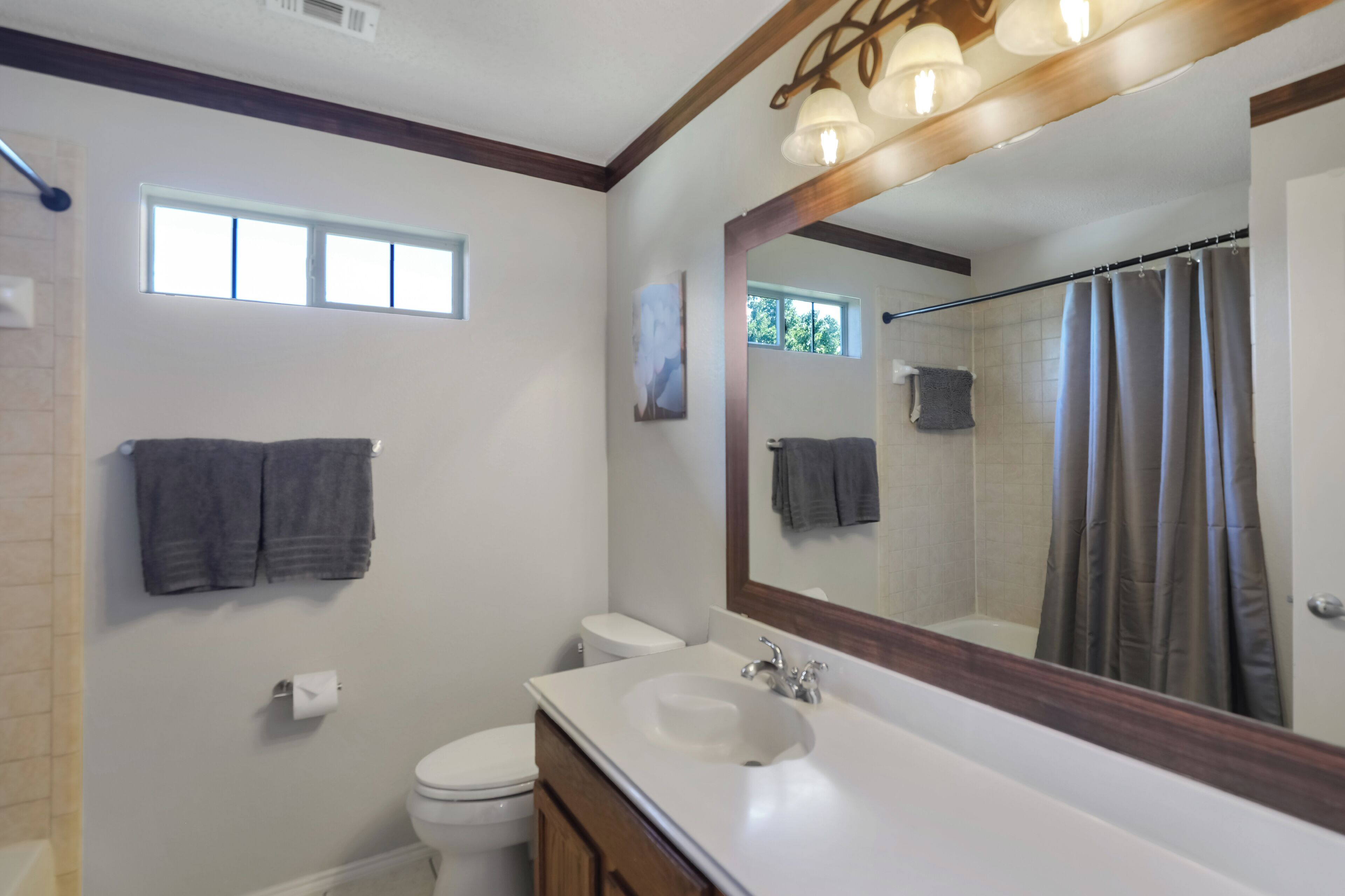 Une salle de bain avec un lavabo blanc, un miroir, des toilettes et un rideau de douche.