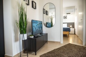 Een moderne woonkamer met een flatscreen-televisie, een grote spiegel en een potplant.
