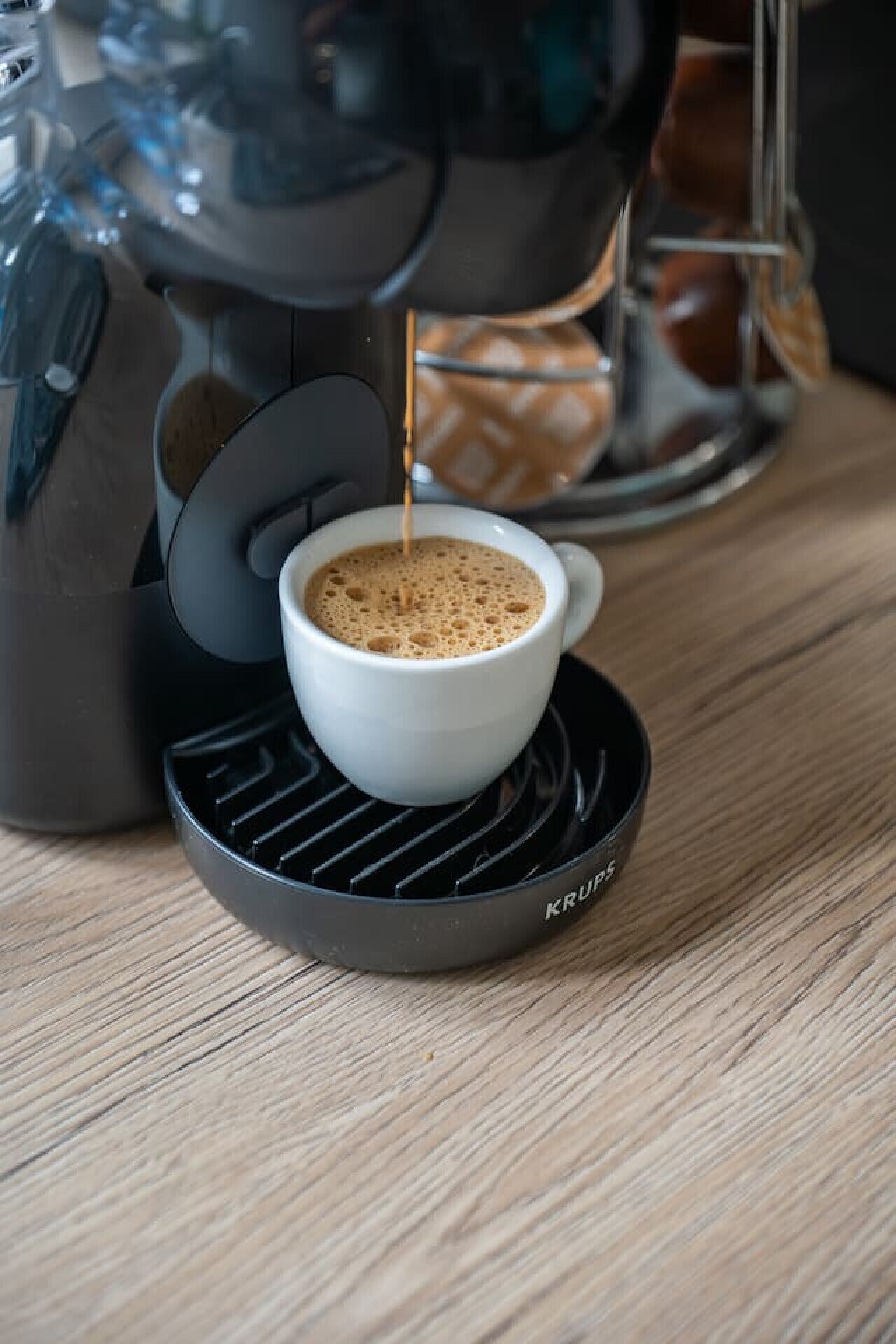 Una macchina per il caffè versa il caffè in una tazza bianca su un piattino nero.
