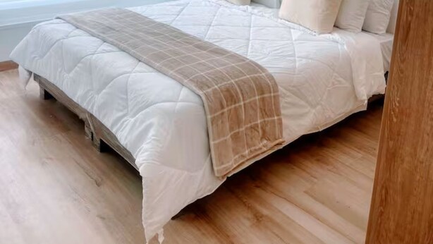 Een slaapkamer met een groot bed, houten vloeren en een raam met zonwering.