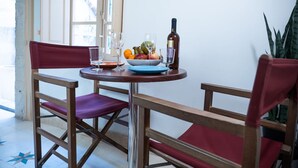 A dining table with a bowl of fruit, a bottle of wine, and glasses. There are two chairs with red cushions. - Casa San Carlo Valletta - Amarillo (Valletta)