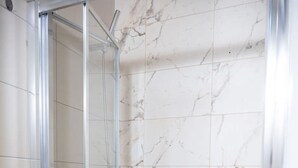 A glass-enclosed shower with a marble wall. - Casa San Carlo Valletta - Amarillo (Valletta)
