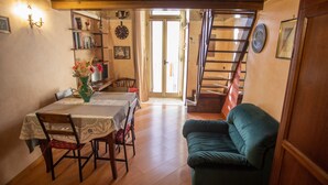 Ein Essbereich mit Tisch, Stühlen und einem grünen Sofa. Eine Treppe führt zu einer anderen Ebene.