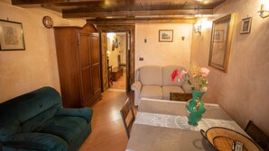 Ein gemütliches Wohnzimmer mit einem grünen Sofa, einem beigen Sofa, einer Holzkabine und einem Esstisch mit einer Blumenvase.