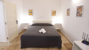 A hotel room with a large bed, two bedside tables, a door, and artwork on the walls. - The George Studio at Grand Harbour View Flats (Il-Furjana)