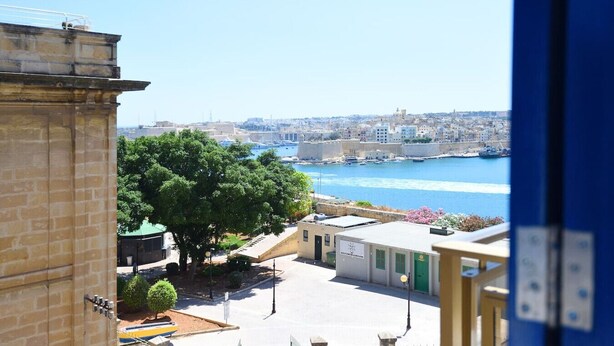 Paisatge urbà costaner amb vista al mar, edificis i un arbre al primer pla.