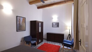 Habitació amb llit, dues cadires, armari, escriptori amb làmpada i ventilador de sostre.
