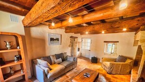 A cozy living room with a wooden ceiling, a sofa, a coffee table, and a stone fireplace.