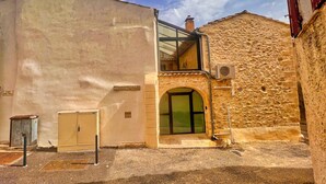 A building with a stone facade, a glass entrance, and a small air conditioning unit mounted on the wall.