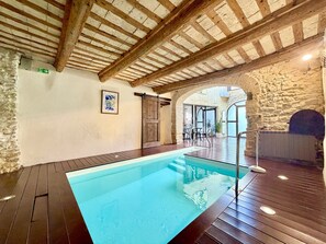 Une piscine intérieure avec des poutres en bois et des murs en pierre.