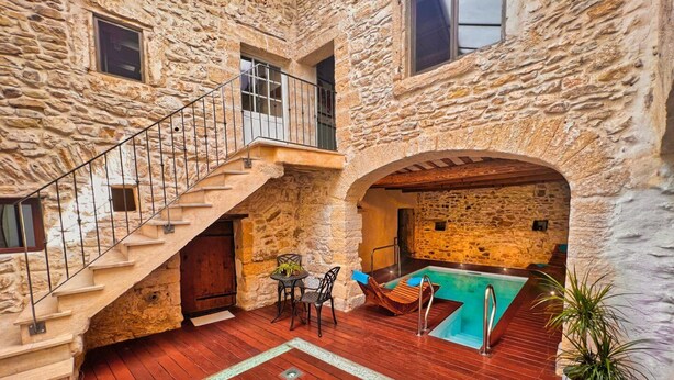 A stone building with a wooden deck, a pool, and a staircase.