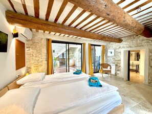 A bedroom with a bed, a chair, and a view of the outside. - P’tit Coin Paradis – Heated Pool & Hot Tub (Saint-Hippolyte-de-Montaigu)