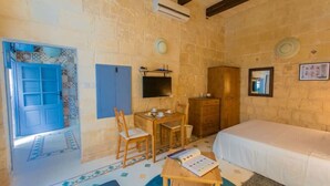A room with a bed, a desk with a chair, a wardrobe, and a television. - Casa San Carlo Valletta - Azure (Valletta)