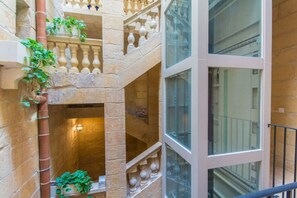 Un intérieur à plusieurs niveaux, avec des murs en pierre, un escalier central et de grandes fenêtres.