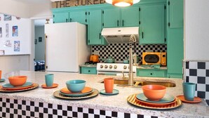Una cocina con gabinetes verde azulado, un refrigerador blanco, un microondas antiguo y un salpicadero a cuadros.