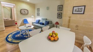 A living room with a white table, blue chairs, a blue rug, a grey sofa, and a clock on the wall.