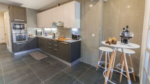A modern kitchen with dark grey cabinets, a built-in oven, and a central island with stools.