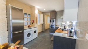 A modern kitchen with stainless steel appliances, a washing machine, and a central island with a toaster.