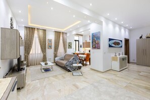 A modern living room with a sofa, coffee table, and artwork on the walls. - Valletta - Deluxe 3 Bedroom Apartment (Il-Belt Valletta)