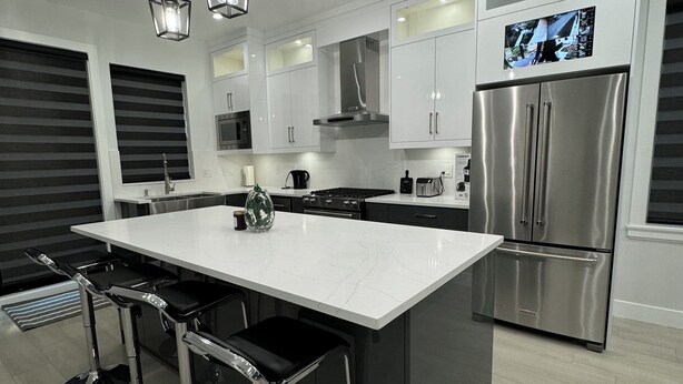 A modern kitchen with a central island, stainless steel appliances, and pendant lighting.