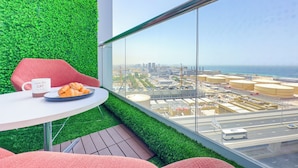 Ein modernes Zimmer mit grüner Wand, Blick auf die Stadt, einem Tisch mit Croissants, einer Tasse und einem roten Stuhl.