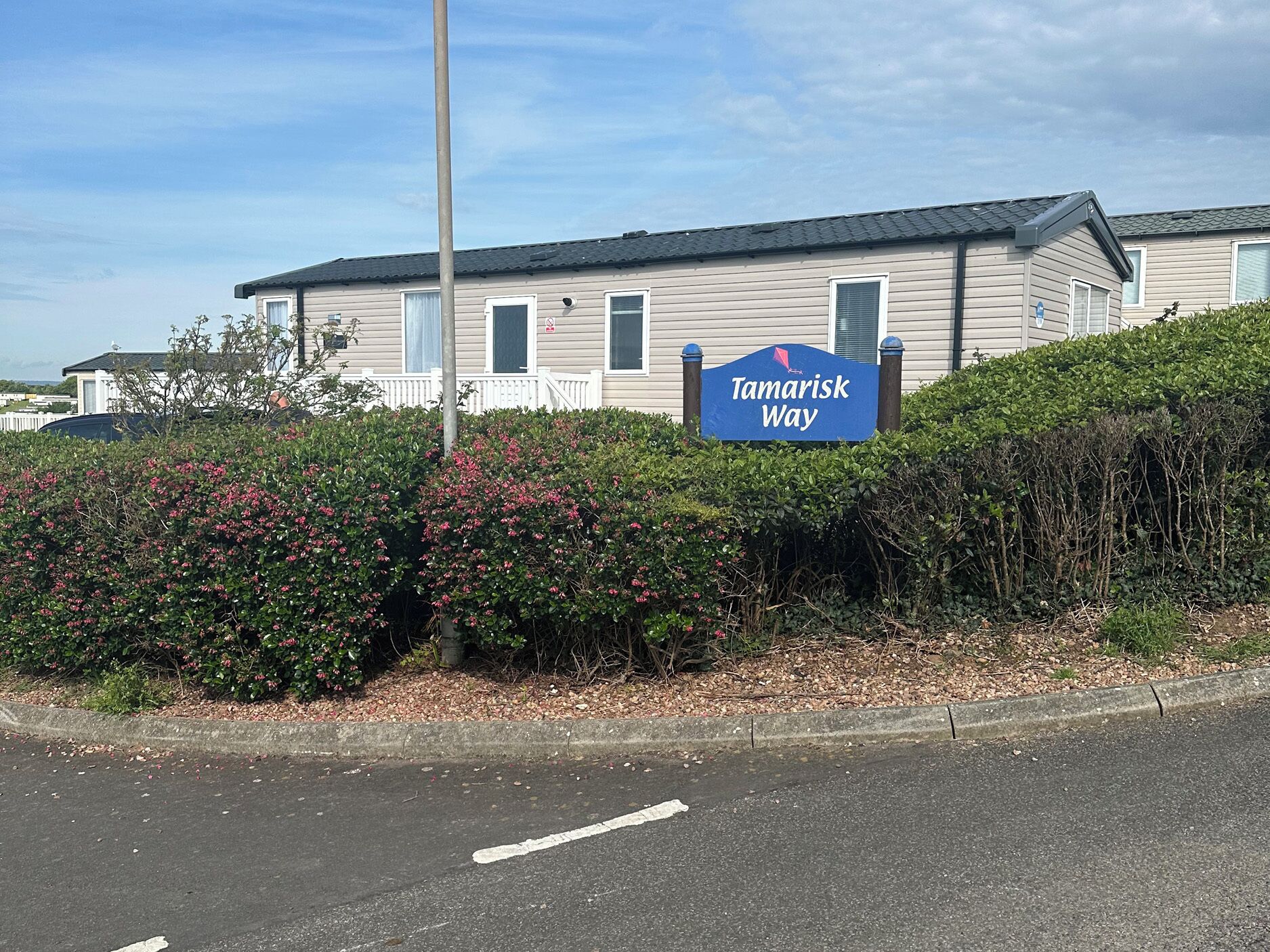 A sign for 'Tamarisk Way' with a building in the background.