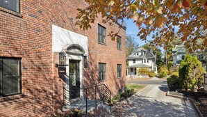 A brick building with a white door, a small porch with steps, and a mailbox labeled "ALBERTINE."