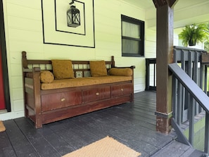 A wooden bench with storage drawers, a lantern, and a window with curtains.