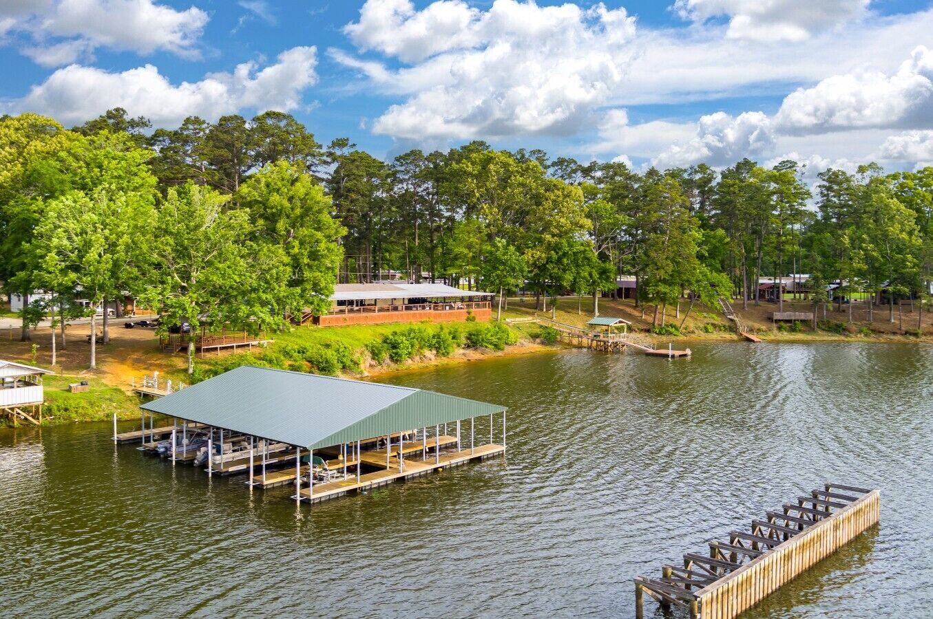 A lakeside property with a dock, a covered pavilion, and a wooden deck.
