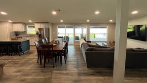 A spacious open-plan living area with a dining table, chairs, a sofa, and a kitchen in the background. - Mid Lake Campground (Hemphill)