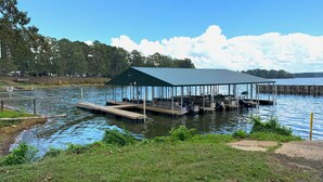 A dock with a covered seating area and boats, surrounded by water and trees. - Mid Lake Campground (Hemphill)