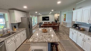 A modern kitchen with white cabinets, granite countertops, and a central island. - Mid Lake Campground (Hemphill)