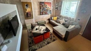 A living room with a sofa, a coffee table, a TV, and artwork on the walls. - Elena's house, is a dream retreat for every type of guest (Sannicandro di Bari)